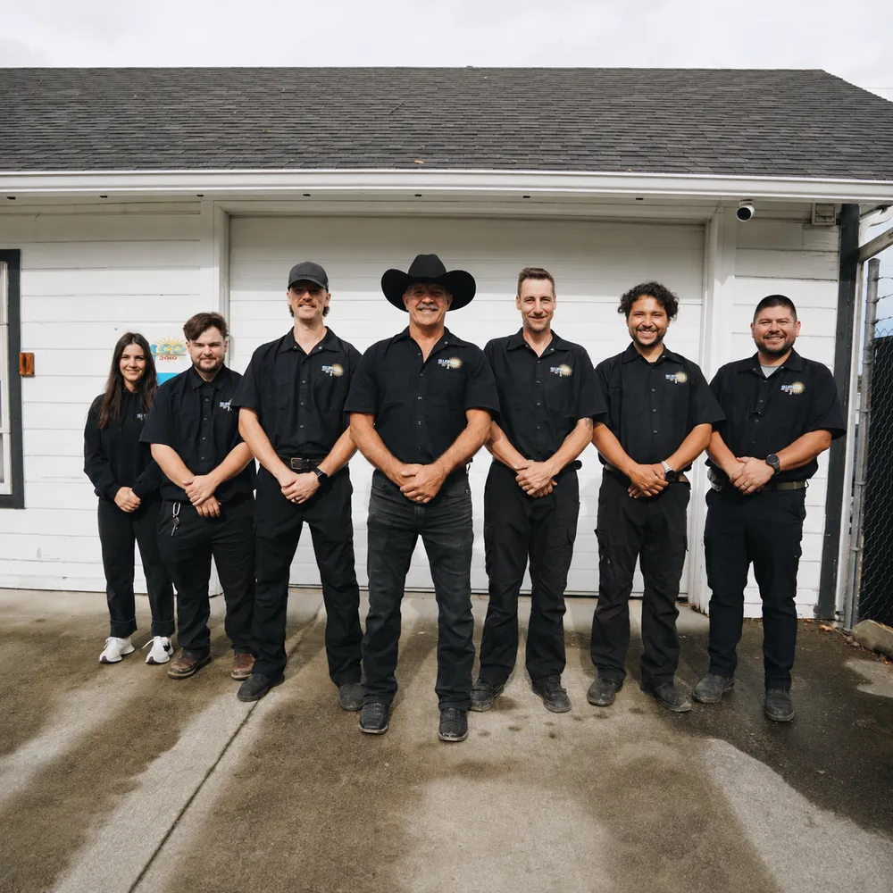 Group photo of seven uniformed Sunco Window Cleaning staff members standing in front of garage door